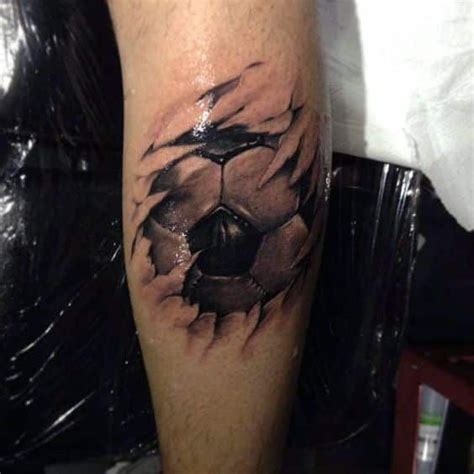 A Tattoo On The Leg Of A Man With A Soccer Ball Coming Out Of It