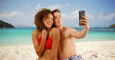 Beautiful Young Couple Using Smartphone To Take Selfie On Beach Stock