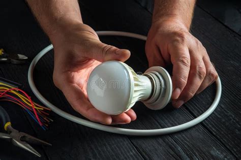 Master Electrician Turns On Light Bulb Close Up Of Worker Hands On A