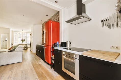 Una cocina con gabinetes rojos y electrodomésticos negros en la pared