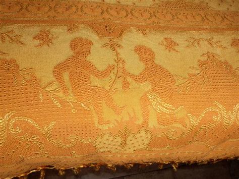 An Old Yellow Cloth With Two Figures On It And Fringe Trimming Around