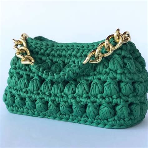 A Green Crocheted Purse With Gold Chains On The Handles And Bottom