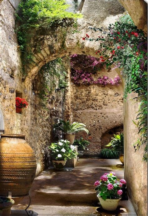 An Alley Way With Potted Plants And Flowers On Either Side Surrounded