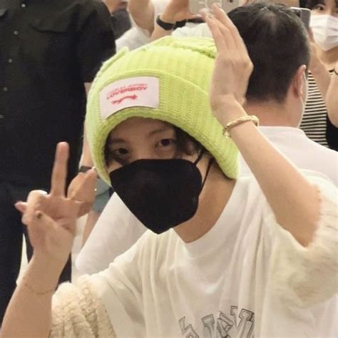 A Person Wearing A Face Mask And Making The Peace Sign With One Hand