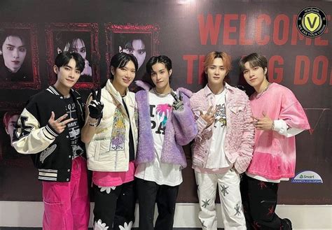 Group Of Young Men Standing Next To Each Other In Front Of A Welcome Sign