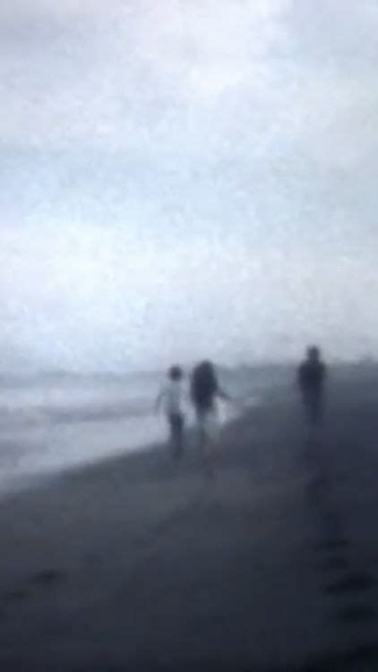 Three People Are Walking Along The Beach On A Foggy Day