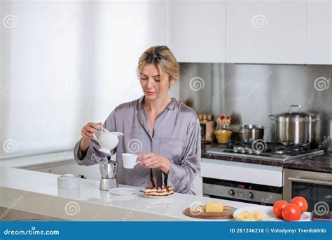 Beautiful Woman Pouring Milk In Coffee Near Table On Kitchen At Home