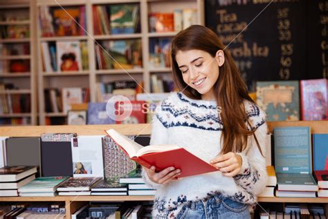 Portrait of a smiling girl reading book indoors in library Royalty-Free Stock Image - Storyblocks