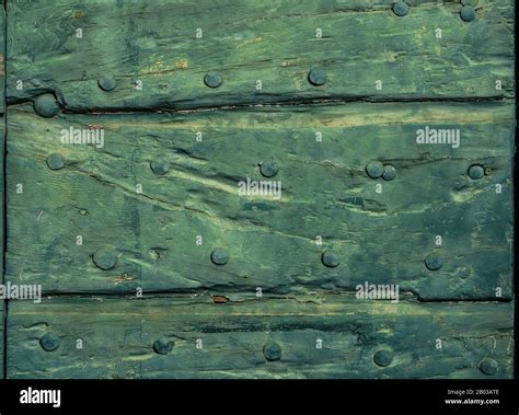 Old Wooden Door With Green Varnish Cracks And Iron Studs As Background