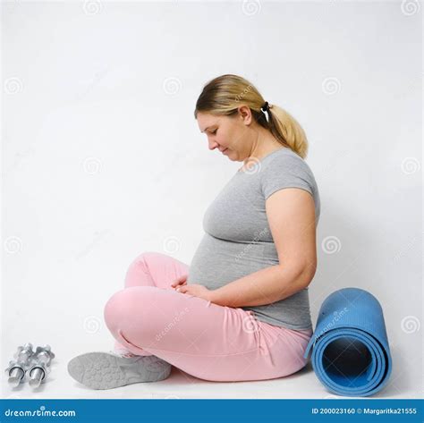 Caucasian Pregnant Woman Sitting On Her Knees On White Background Stock