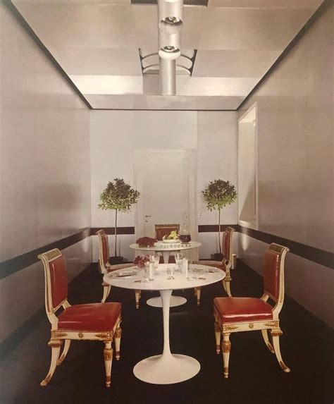 A White Table With Four Chairs Around It In A Room That Has Black And