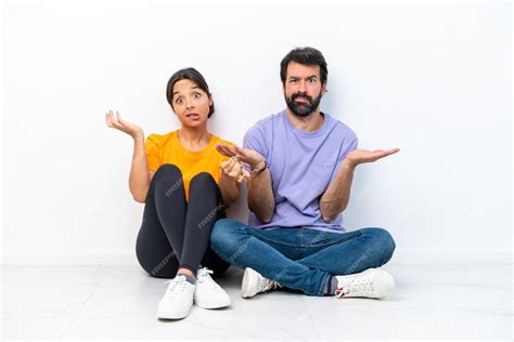 Premium Photo Young Caucasian Couple Sitting On The Floor Isolated On