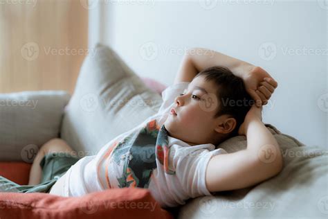 Portrait young boy with curious face sitting on sofa watching cartoon ...