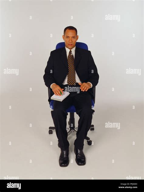 Man In A Business Suit And Tie Sitting In Office Chair With A Notepad