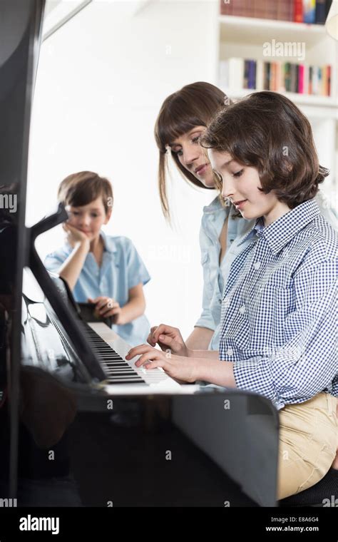 Madre E Hija Tocando El Piano Mientras El Hermano Escuchando Fotograf A