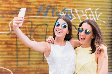 Mujeres Jovenes Que Toman El Selfie Mientras Que Se Coloca En La Calle