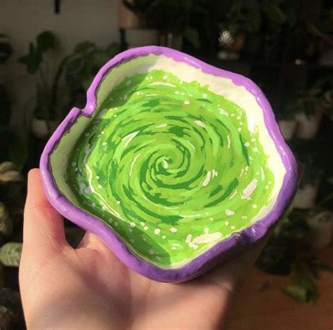 A Hand Holding A Bowl With Green Liquid In It