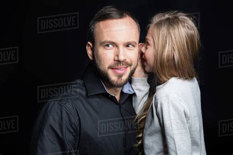 Smiling Father And Daughter Sharing Secrets Isolated On Black Stock