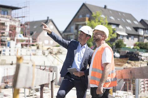 man  suit talking  construction worker  construction site stock photo