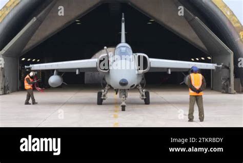 Soldiers check a stationary military jet in front of the hangar before ...