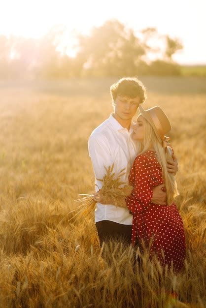 Joven pareja feliz abrazándose en un campo de trigo al atardecer