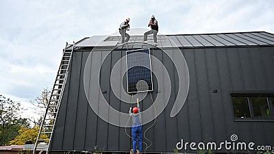 Workers Lifting Up Photovoltaic Solar Module While Installing Solar