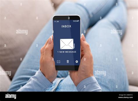 Woman Reading E Mail Message On Smartphone Sitting On Couch Indoor