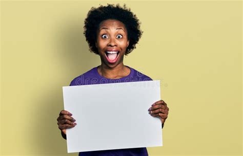 African American Woman With Afro Hair Holding Blank Empty Banner Celebrating Crazy And Amazed