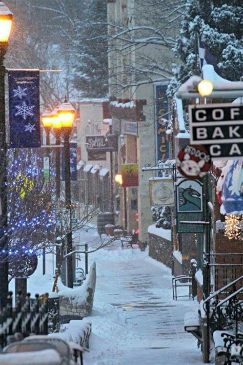 a city street covered in snow with lots of lights and signs on the side ...