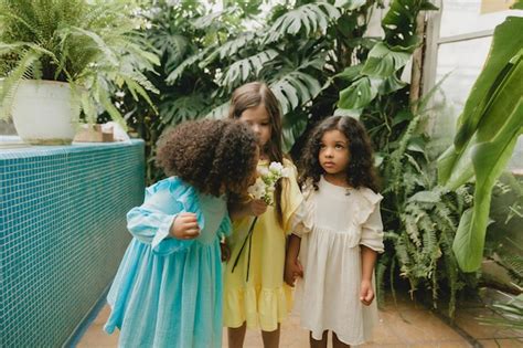 Tres Meninas No Jardim - Três meninas no jardim com flores nas mãos, crianças de diferentes ...