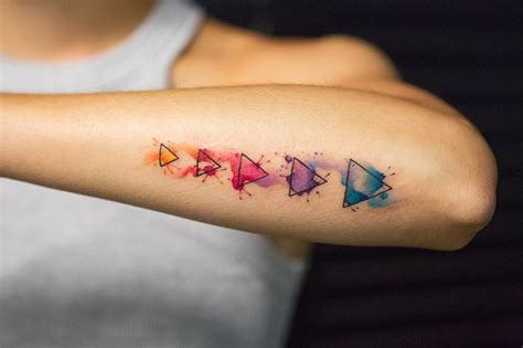 A Woman S Arm With Colorful Watercolor Tattoos On It And Arrows In The