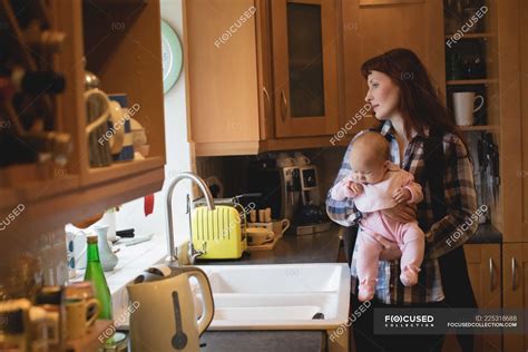 Mother holding little baby in kitchen at home — child, family - Stock ...