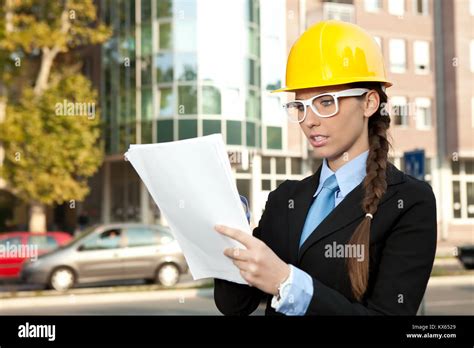 Female Engineer Looking At Blueprints In Construction Site Stock Photo