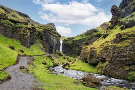 Cascada de kvernufoss que fluye a través del valle verde en un día