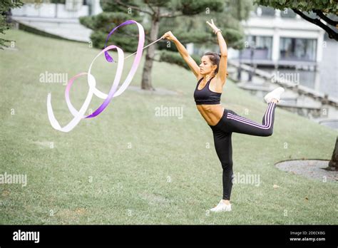 Athletic Woman Practising Rhythmic Gymnastics With A Ribbon Outdoors