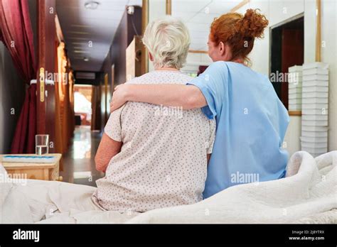 Caring Female Nurse Hugging Sick Old Woman For Comfort In Nursing Home