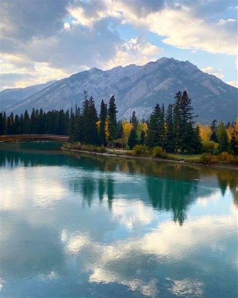 A Lake With Mountains In The Background And Trees On Both Sides That