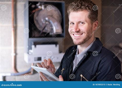 Portrait Of Male Heating Engineer Servicing Central Heating Boiler