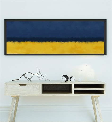 an abstract painting hangs on the wall above a table with a vase and two candles