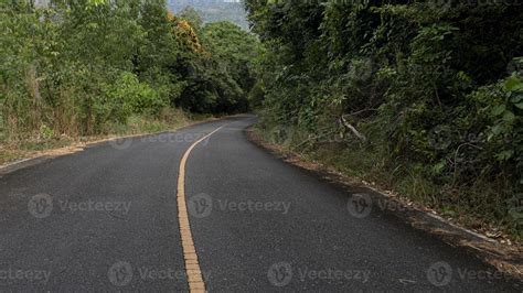 Curvy Road Of Empty Asphalt Road With Yellow Traffic Line And Wet Fron