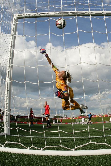 A Soccer Goalie Jumps Up To Catch The Ball