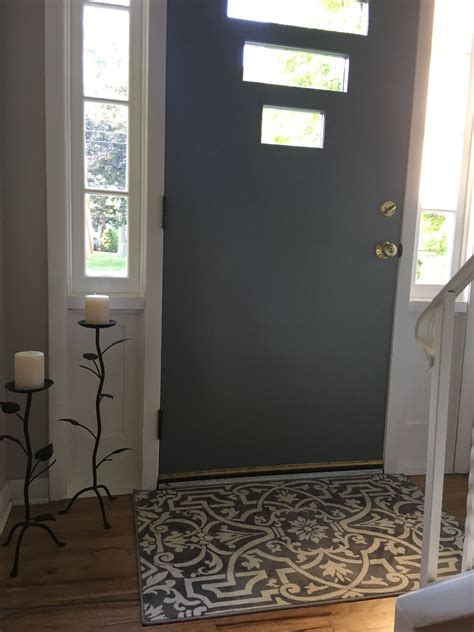 the front door is painted gray and has a decorative rug on the floor ...