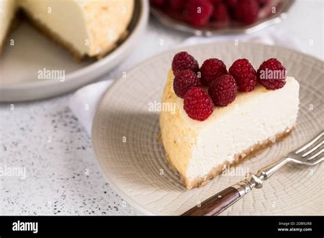 Slice Of Classical New York Cheesecake With Raspberries On White Plate