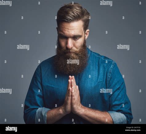 Young Man With A Long Beard With His Hands Clasped Together In Prayer