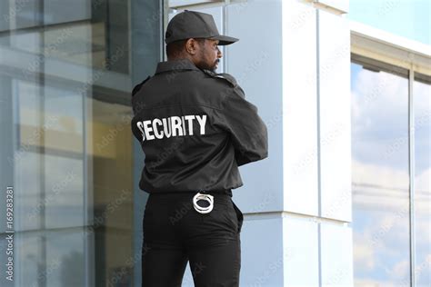 Male Security Guard Standing Near Big Modern Building Stock Photo