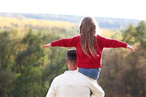 A Happy Child On The Shoulders Of A Parent In A Park In Nature Weekend