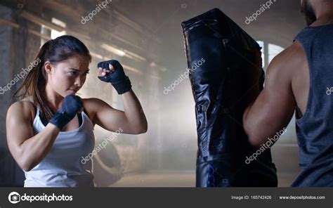 Athletic Woman Trains Her Punches On A Punching Bag That Her Par