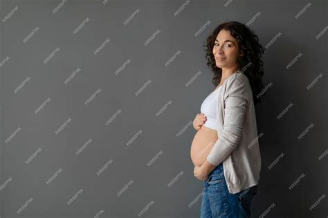 Linda Mulher Grávida Abraçando A Barriga Com Ternura Enquanto Posava