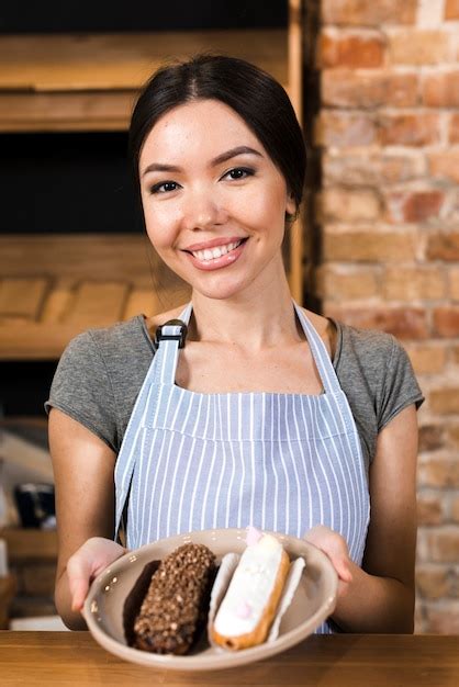 Retrato De Um Sorrindo Mulher Jovem Mostrando Eclairs Em