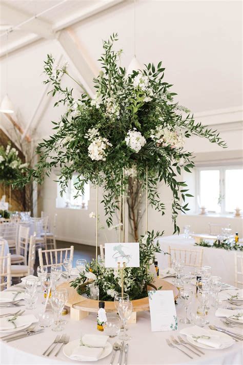 The Centerpieces Are Decorated With Greenery And White Flowers